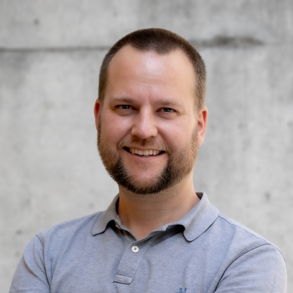 Portraitfoto von Felix Haberstumpf vor einer Betonwand, er lächelt in die Kamera